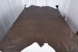 Picture of a dark brown with light undertones distress full grain upholstery leather displayed on a table