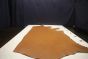 Golden brown colored Italian leather cowhide laying flat on a table 