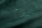 Closeup photo of natural marking on deep green nubuck material. 