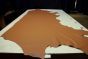 Brandy colored thick leather cowhide laying flat on a table 