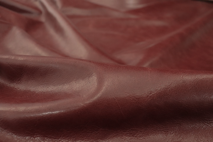 Close up picture of vibrant multitone bordeaux distress leather for upholstery